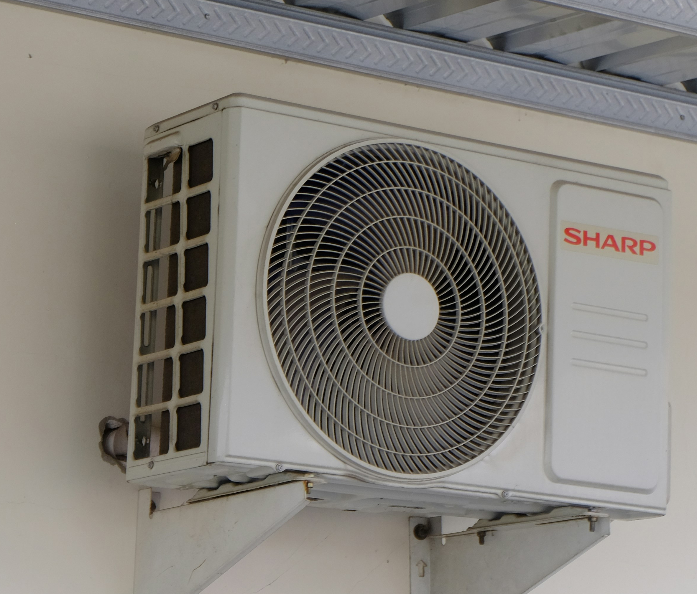 Technician installing a split-system air conditioning unit on the wall of a residential home, wearing uniform and safety gear, focused and professional mood