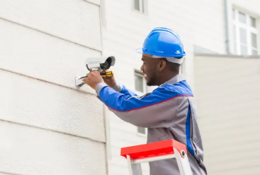 Technician installing a split-system air conditioning unit on the wall of a residential home, wearing uniform and safety gear, focused and professional mood